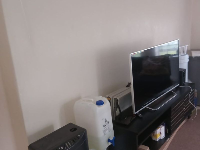 A view of a living room area with plain walls and neutral flooring.