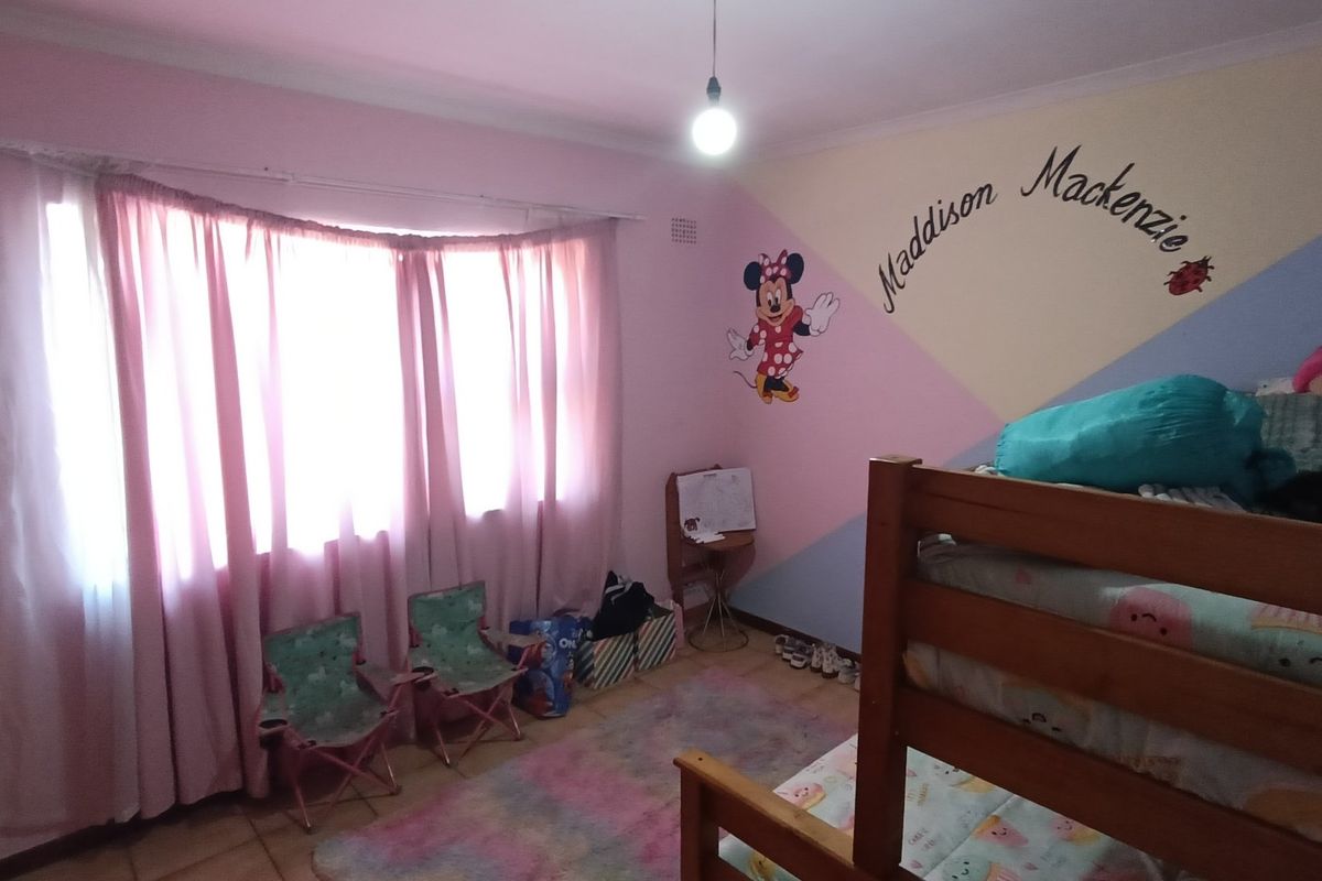 A bedroom featuring a large bay window, tiled flooring, and decorative coving, providing a functional space with natural light.