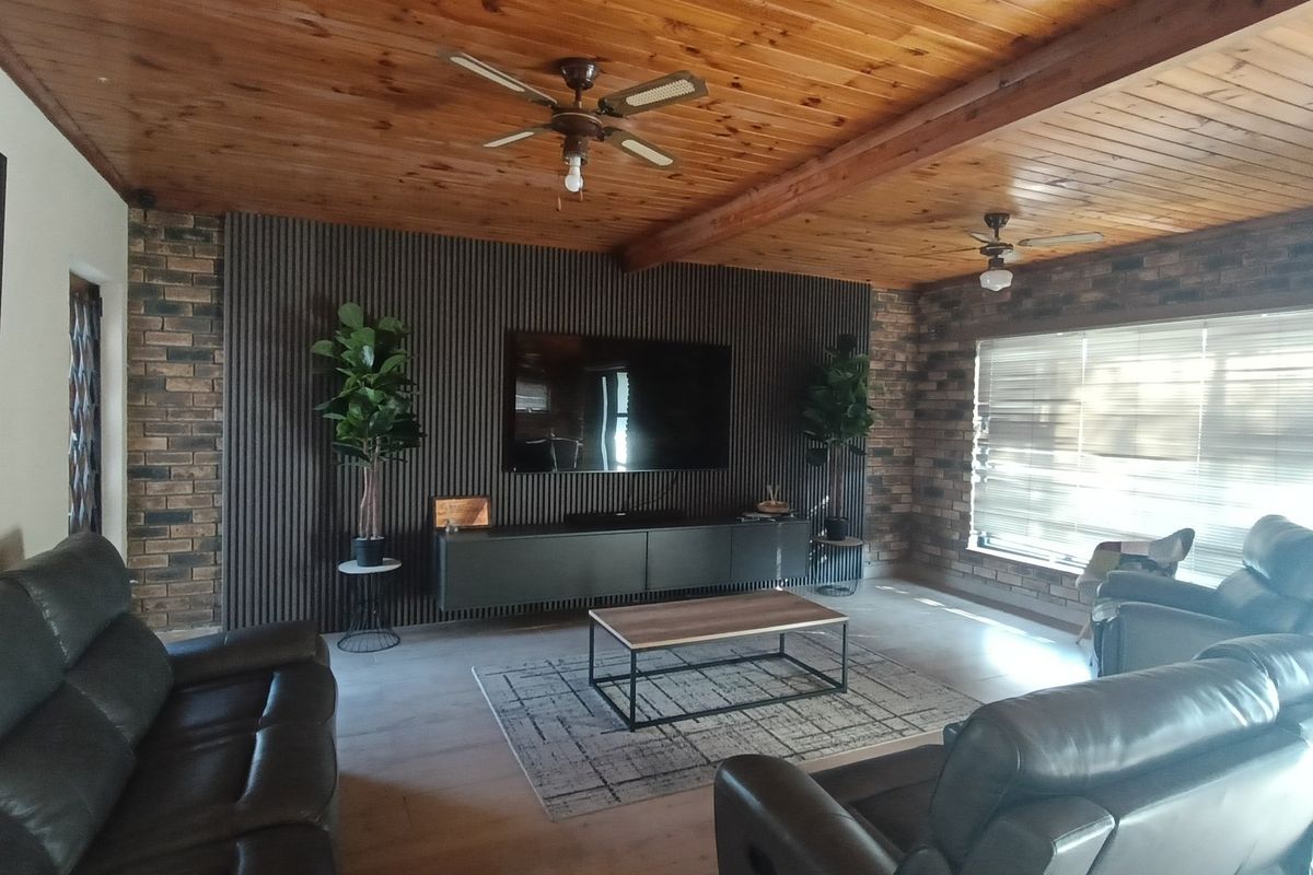Spacious living room featuring a warm timber-clad ceiling, exposed brick walls, and a modern slatted feature wall with integrated media storage.