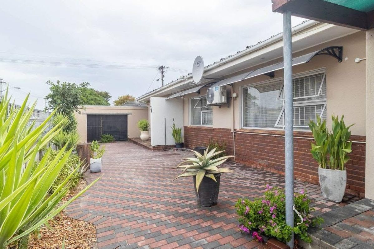 A well-maintained rear exterior area featuring brick paving, a brick-accented facade, and functional window awnings, providing a clean and accessible outdoor space.