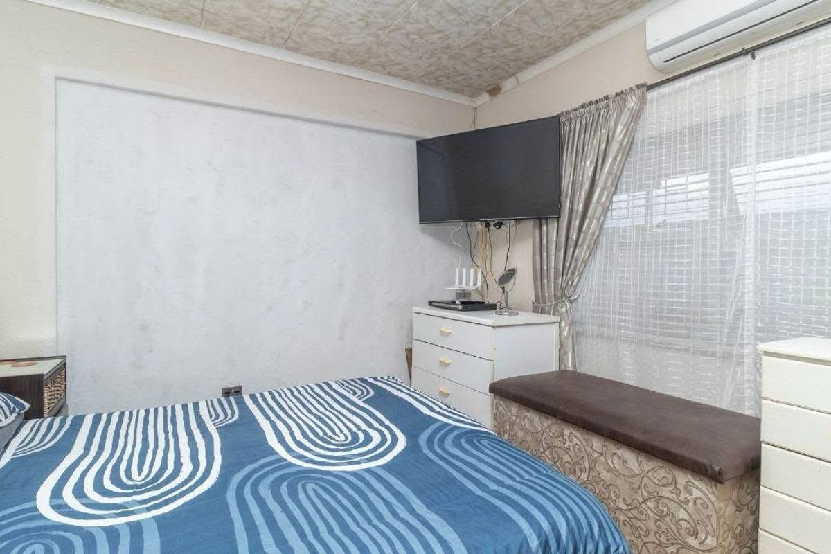 A bedroom featuring a wall-mounted air conditioning unit and a textured ceiling finish.