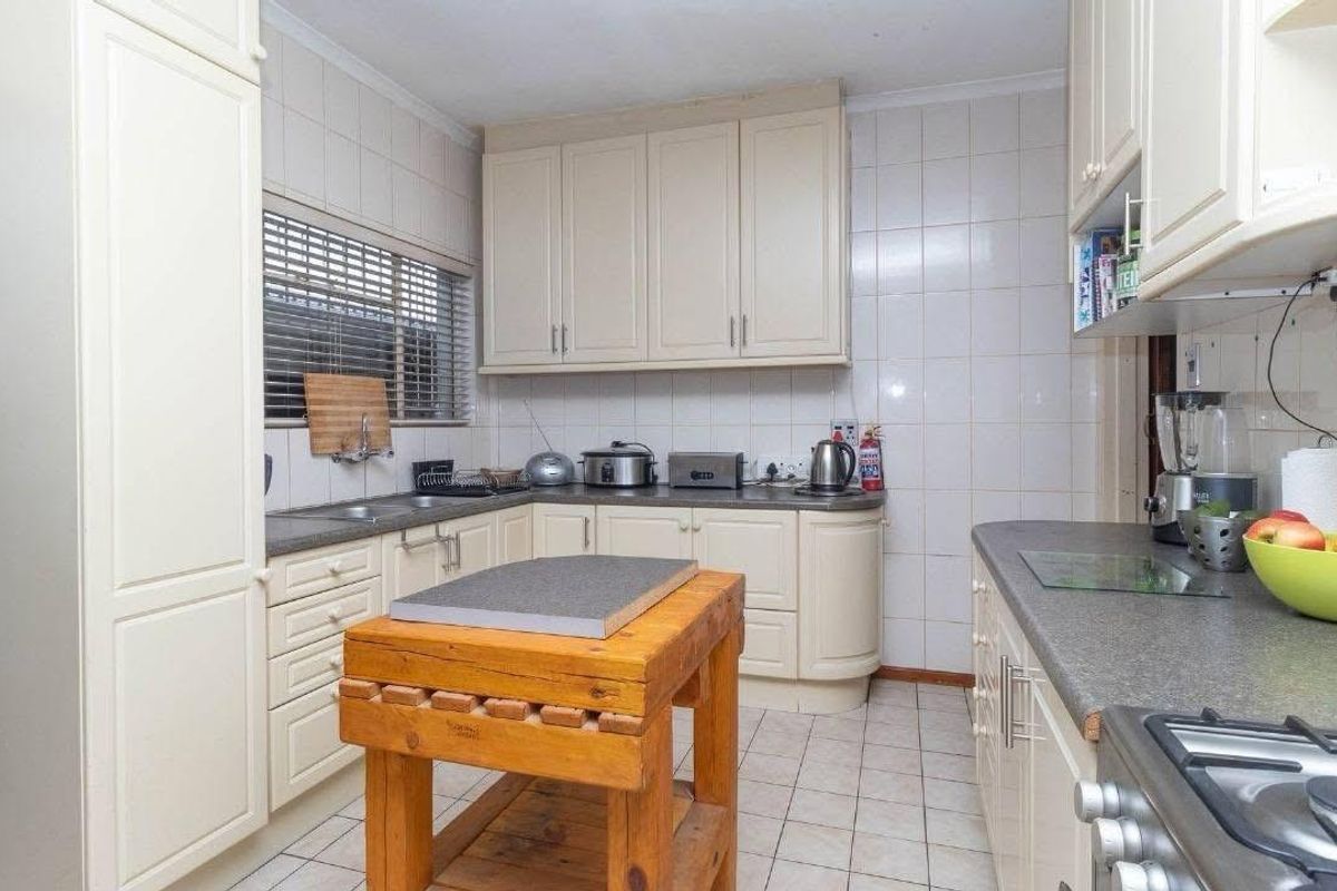 A functional kitchen featuring cream-colored built-in cabinetry, laminate countertops, a gas hob, and tiled finishes throughout.