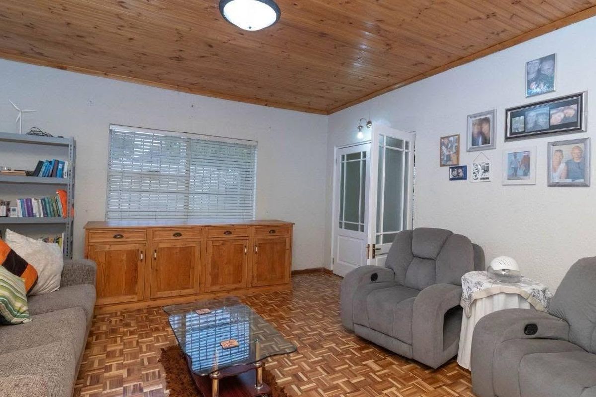 A living room featuring traditional parquet flooring and a warm wooden ceiling, providing a classic foundation for modern interior updates.