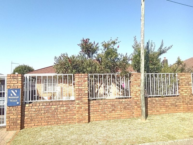 Front view of the property featuring a brick boundary wall with integrated metal security fencing and a tiled roof structure.