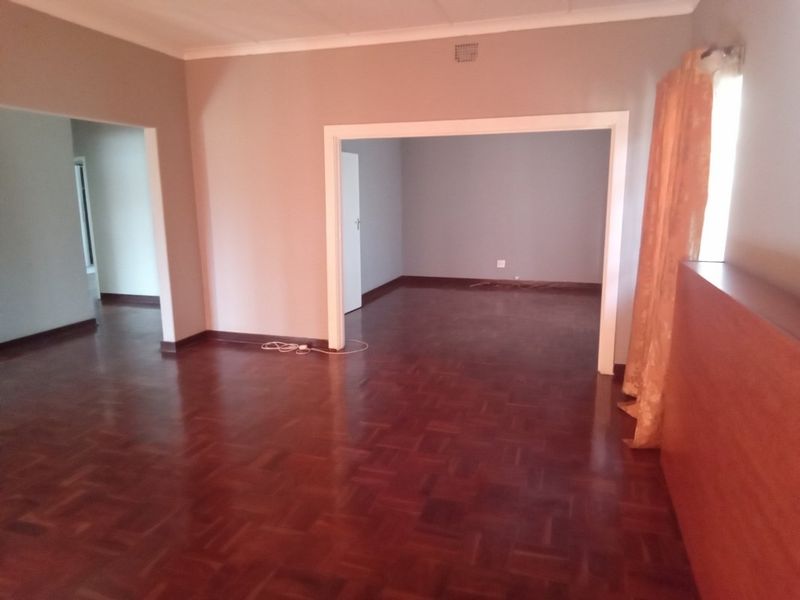 Spacious living area featuring classic parquet flooring and an open-plan layout connecting to adjacent rooms.