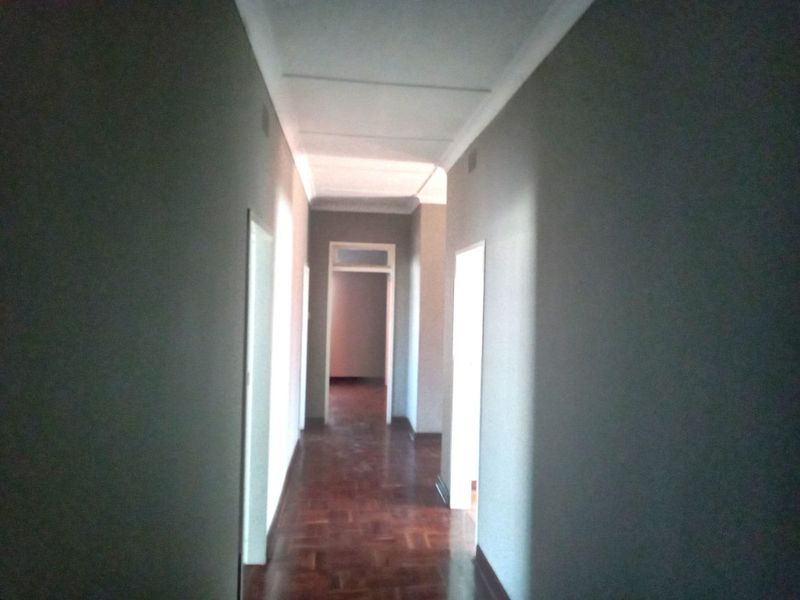 A vacant hallway featuring traditional parquet flooring and coved ceilings, providing access to multiple rooms within the property.