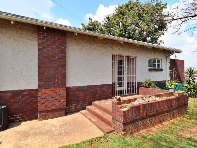 Rear exterior view of the house featuring a brick and plaster facade, concrete steps, and a built-in brick planter box.