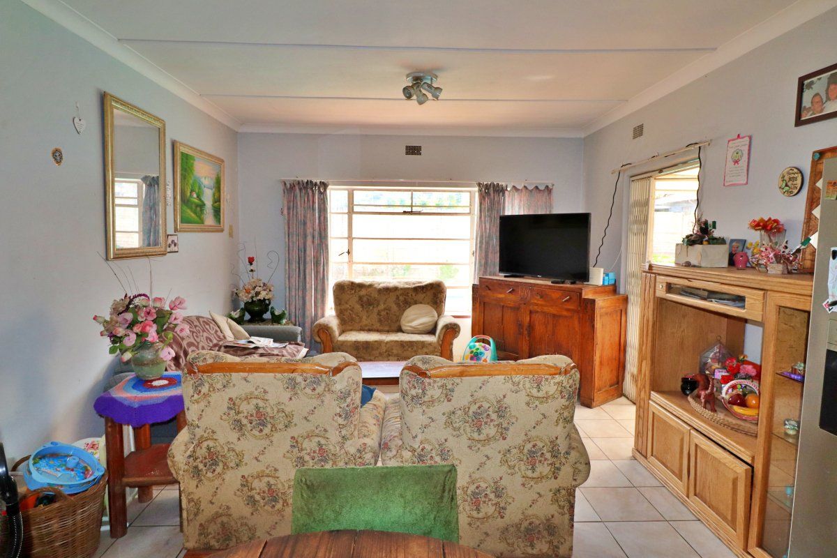 A functional living room featuring tiled flooring, a large window for natural light, and a sliding door providing access to the exterior.