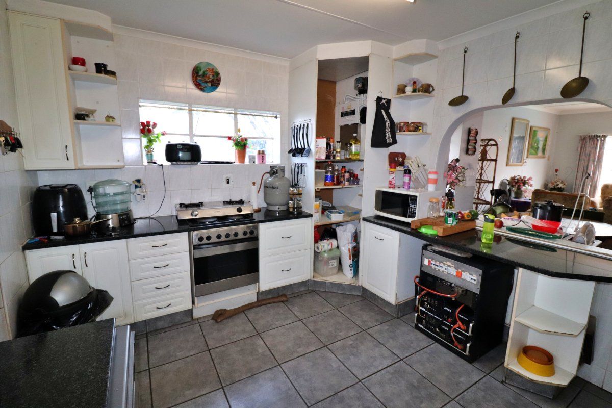A functional kitchen featuring granite countertops, a gas stove, and tiled finishes, offering a practical layout with potential for modern cosmetic updates.