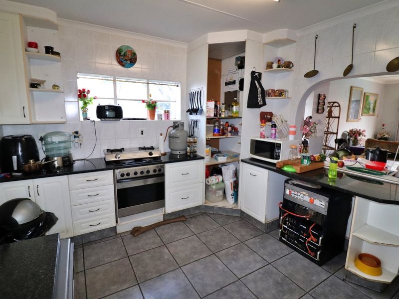 A functional kitchen featuring granite countertops, a gas stove, and tiled finishes, offering a practical layout with potential for modern cosmetic updates.
