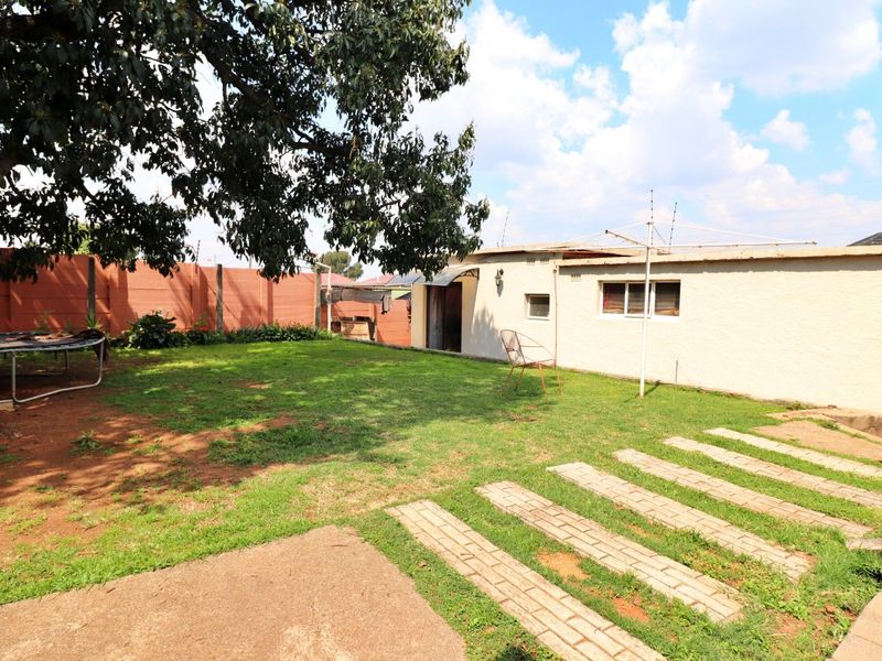 A rear garden area featuring a lawn, paved walkway, and precast concrete boundary wall, providing a private outdoor space for the property.