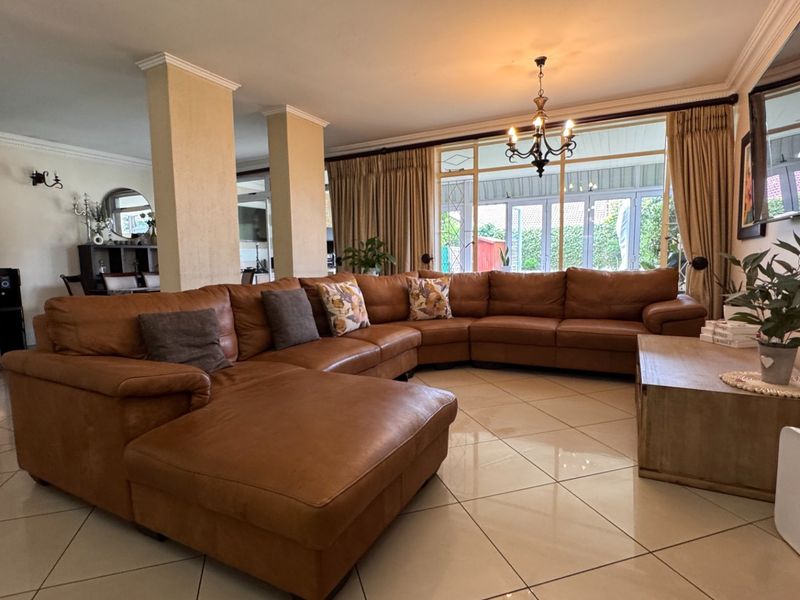 Spacious open-plan living area featuring large windows, tiled flooring, and structural columns, creating a bright and connected space for relaxation.