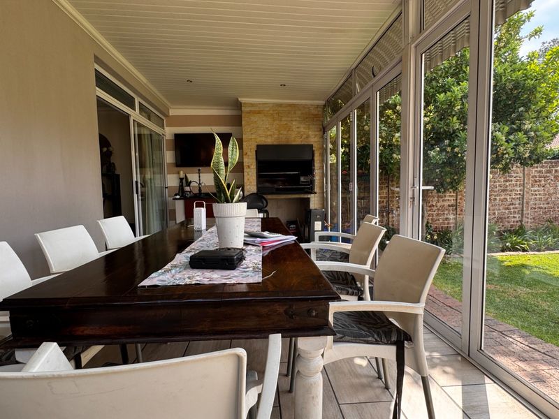 Enclosed patio featuring a built-in braai, stone cladding, and large sliding glass doors that open onto the garden.