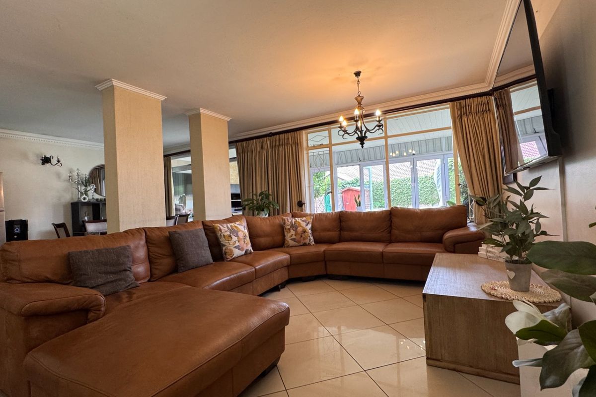 Spacious living area featuring large format floor tiles, structural columns, and expansive glass sliding doors providing natural light and access to the rear patio.