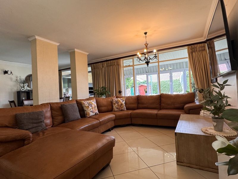 Spacious living area featuring large format floor tiles, structural columns, and expansive glass sliding doors providing natural light and access to the rear patio.