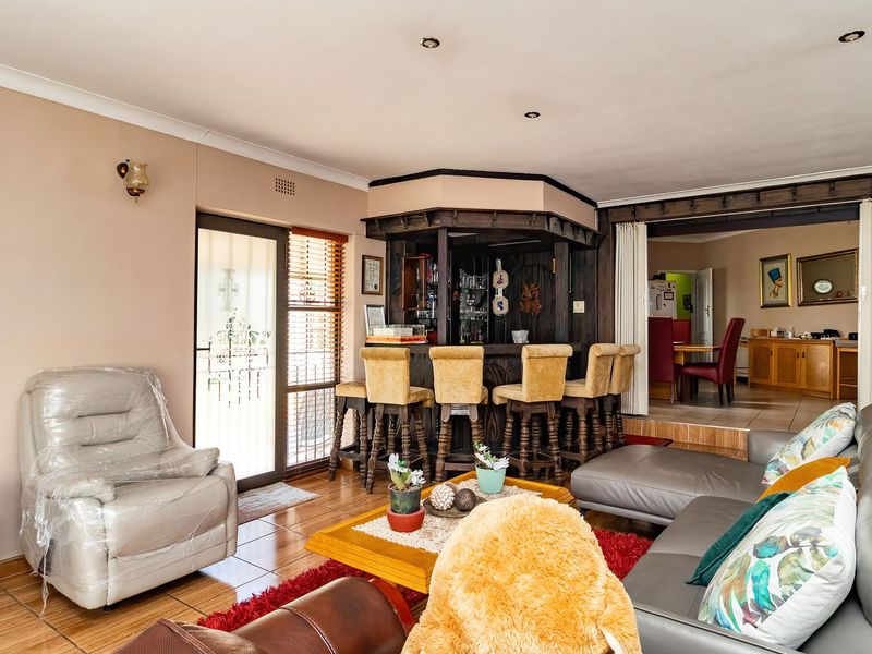 Spacious living area featuring a built-in timber bar, tiled flooring, and direct access to outdoor space, with an adjacent dining area visible.