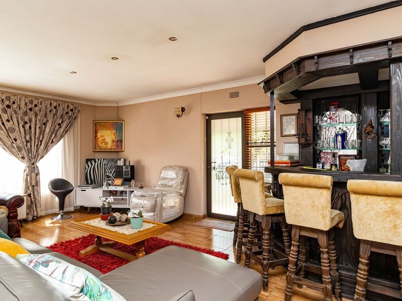 Spacious living area featuring a built-in wooden bar, tiled flooring, and recessed lighting, offering a functional space for relaxation and entertainment.