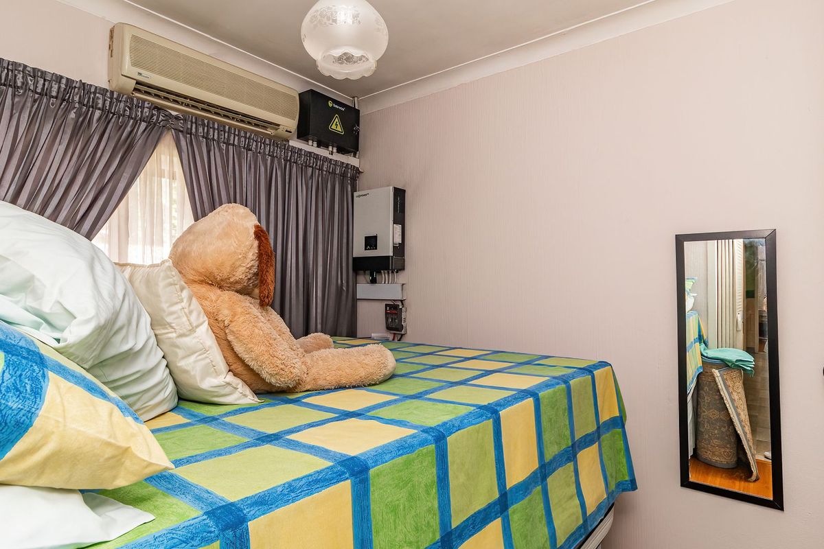 A bedroom featuring a wall-mounted split-system air conditioner, solar inverter system, and built-in wardrobe storage.