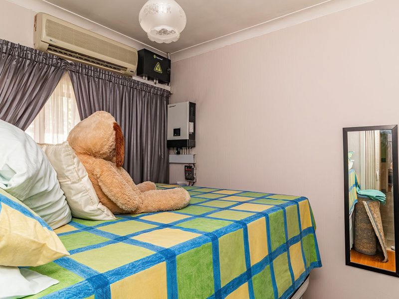 A bedroom featuring a wall-mounted split-system air conditioner, solar inverter system, and built-in wardrobe storage.