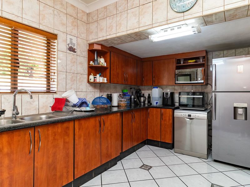 A functional kitchen featuring wooden cabinetry, granite countertops, tiled backsplash, and tiled flooring, offering a practical layout for daily meal preparation.