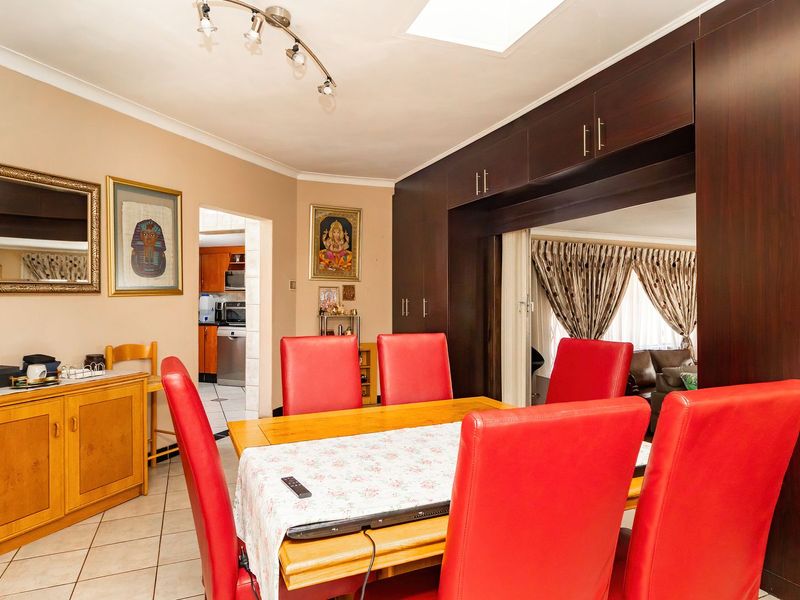 A dining room featuring dark wood built-in cabinetry, tiled flooring, and a skylight, with an open transition to the kitchen area.