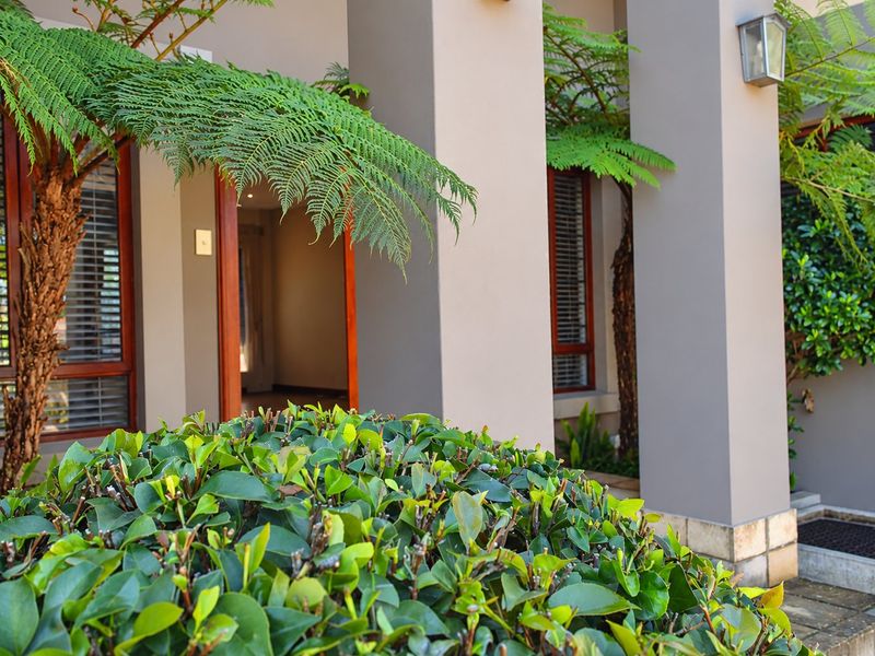 A well-maintained townhouse entrance featuring structural pillars, timber-framed windows, and stone base detailing, providing a welcoming and modern facade.