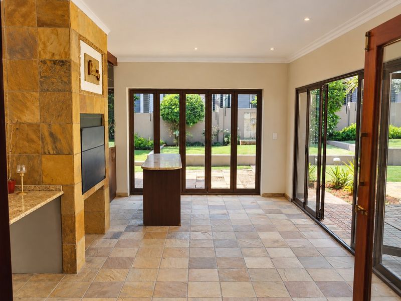 Spacious open-plan living area featuring a stone-clad fireplace, tiled flooring, and large bi-fold glass doors providing seamless access to the garden.