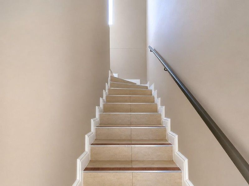 A clean, well-maintained staircase featuring tiled treads and a modern handrail, leading to an upper level.