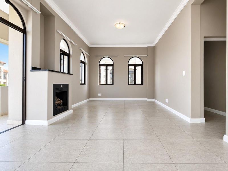 Spacious, light-filled living room featuring neutral tiled floors, a built-in fireplace, and elegant arched windows with access to an outdoor patio area.