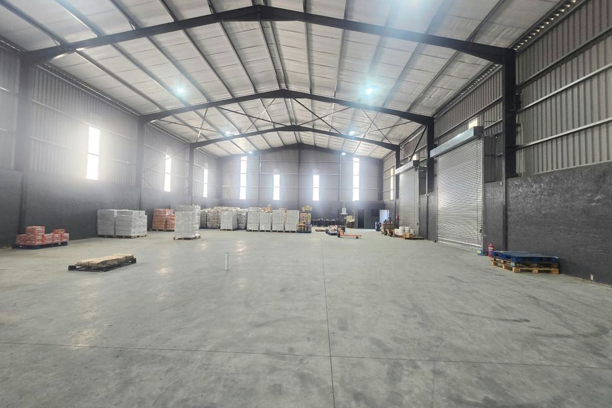 Spacious industrial warehouse featuring high ceilings, concrete flooring, steel portal frame construction, and a large roller shutter door for efficient access.