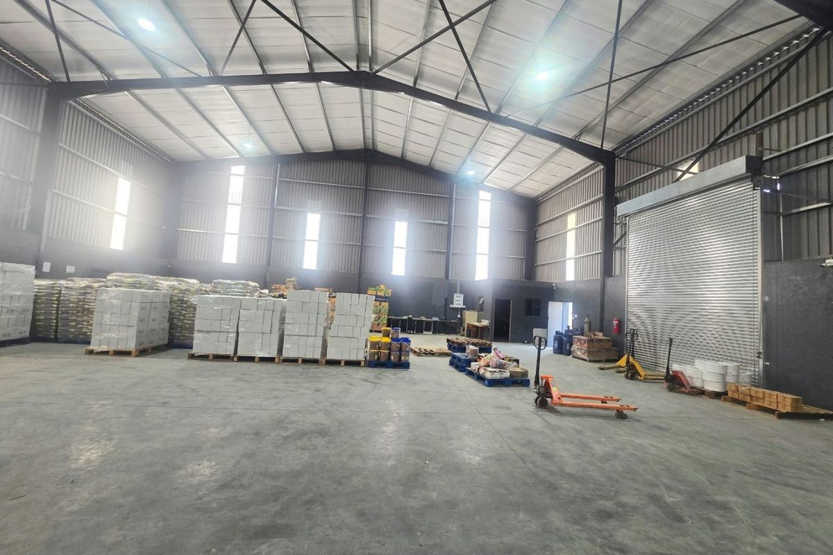 Spacious industrial warehouse featuring a high-clearance steel portal frame, concrete flooring, and a large roller shutter door for efficient logistics and storage operations.