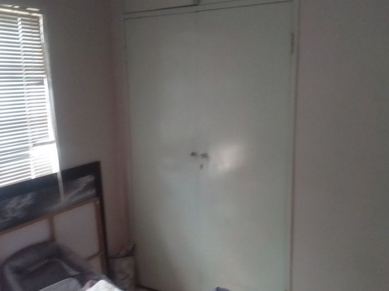 A bedroom featuring a built-in wardrobe and a window fitted with venetian blinds.