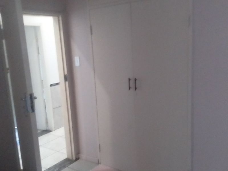 A simple hallway featuring a built-in cupboard and access to an adjacent room.