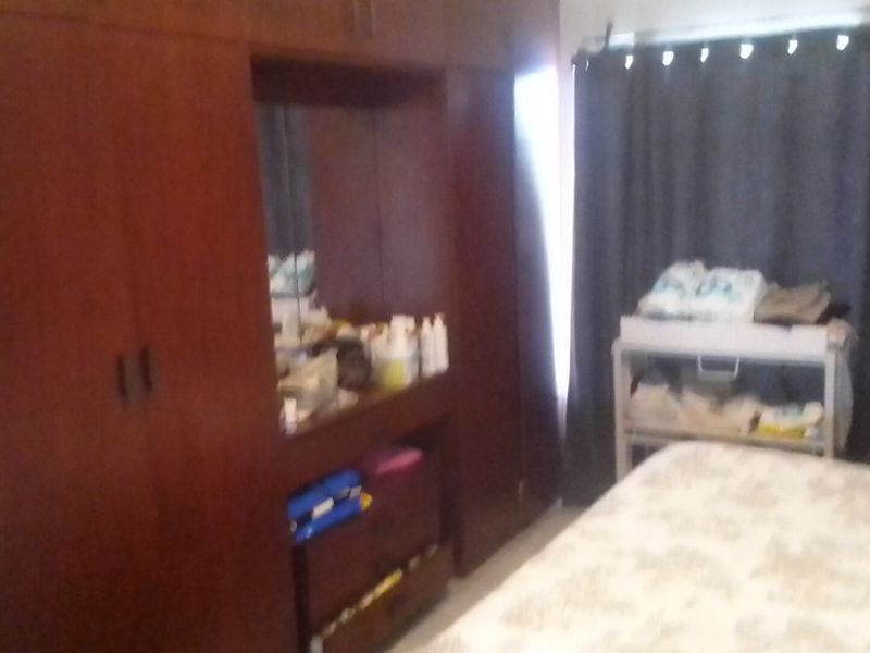 A bedroom featuring a large, dark wood built-in wardrobe with an integrated vanity mirror and storage drawers.