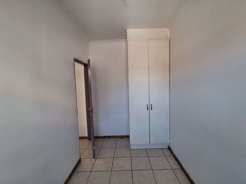 A clean, empty bedroom featuring neutral tiled flooring and a built-in wardrobe, offering a blank canvas for personalization.