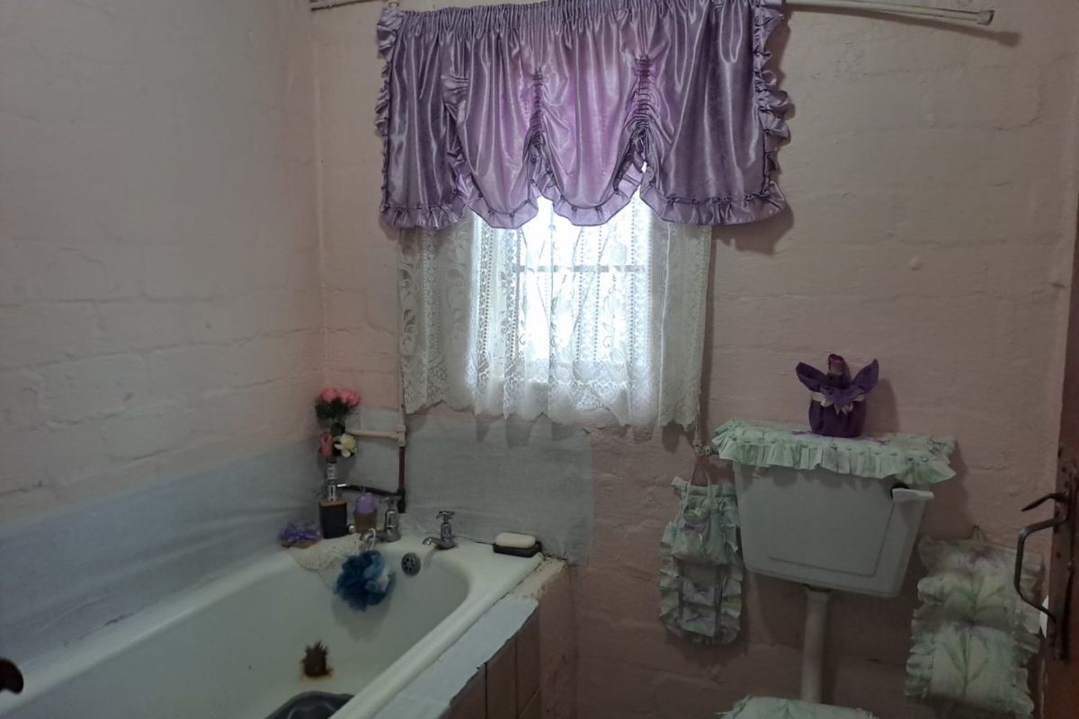 A dated bathroom featuring a standard bathtub and toilet with exposed brick walls, requiring modernization and cosmetic updates to improve functionality and aesthetic appeal.