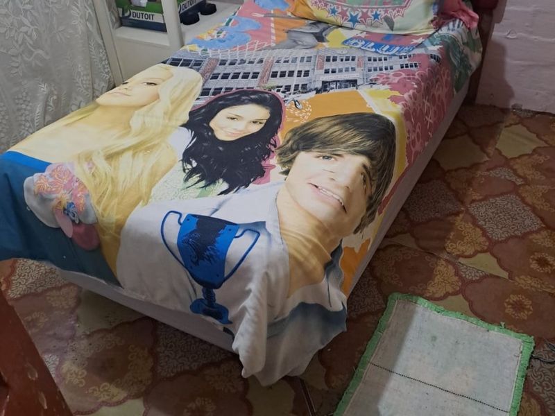 A compact bedroom featuring patterned floor tiles and a single bed setup.