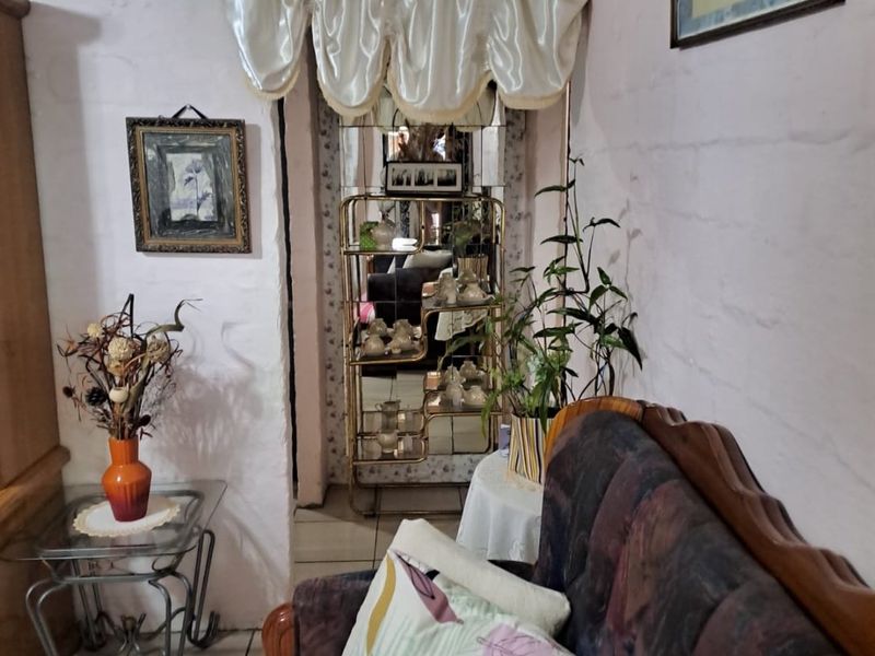A living area featuring textured walls and tiled flooring, providing a dated foundation ready for modern updates and interior design improvements.