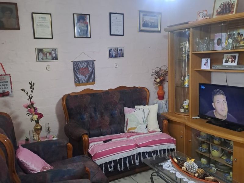 A living room featuring tiled flooring and a built-in wooden display cabinet, with visible wall texture and cracks requiring maintenance.