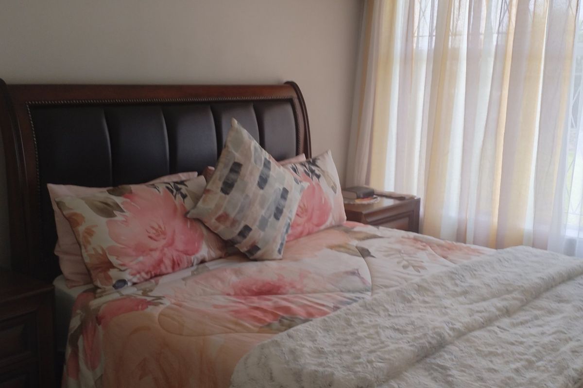 A cozy bedroom featuring a window with security bars and neutral wall finishes, providing a comfortable and functional sleeping space.