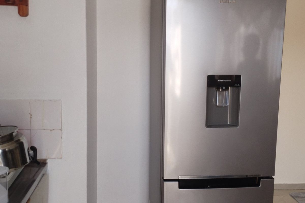 A kitchen area featuring a tiled splashback and countertop space, showing signs of wear in the tiling.