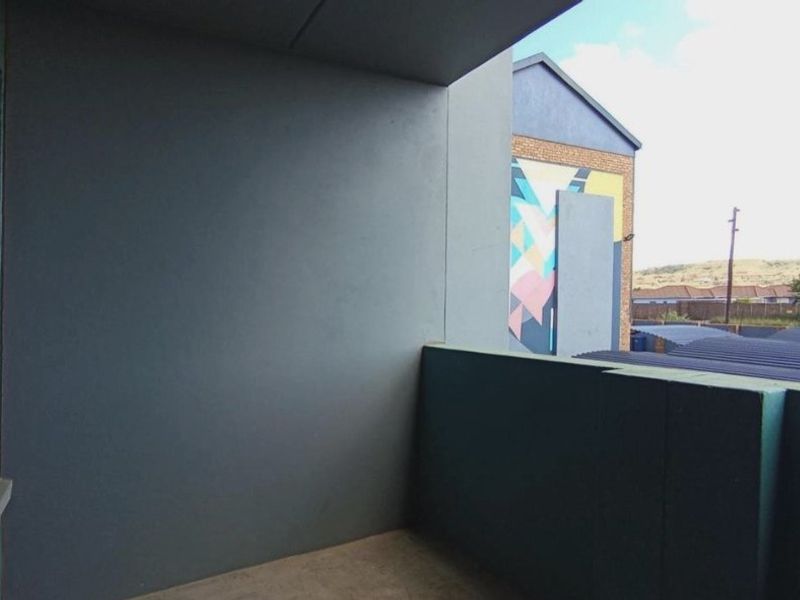 A covered balcony area with painted masonry walls and concrete flooring, offering an open outdoor space.