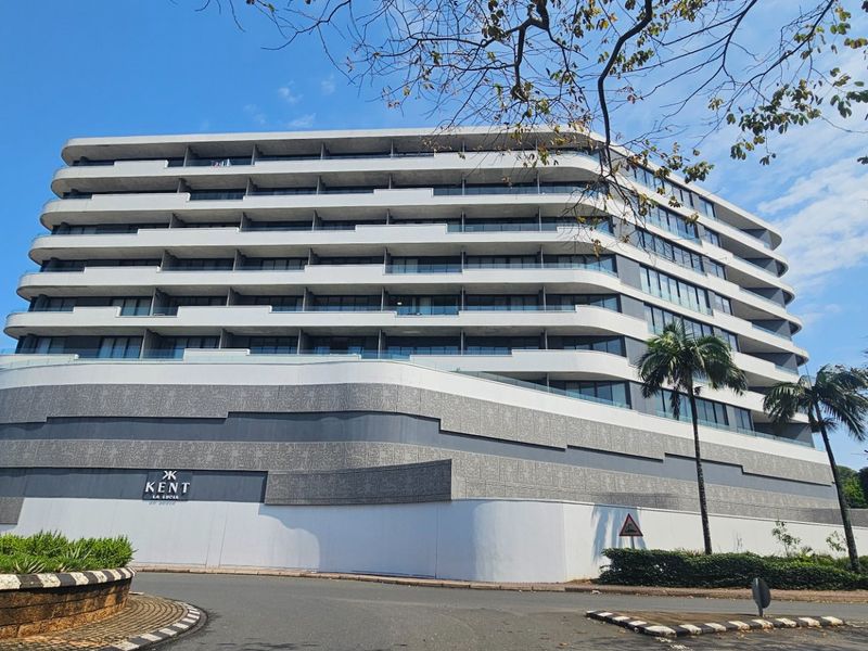 A modern multi-story apartment building featuring contemporary architectural design, layered balconies with glass balustrades, and textured facade detailing.