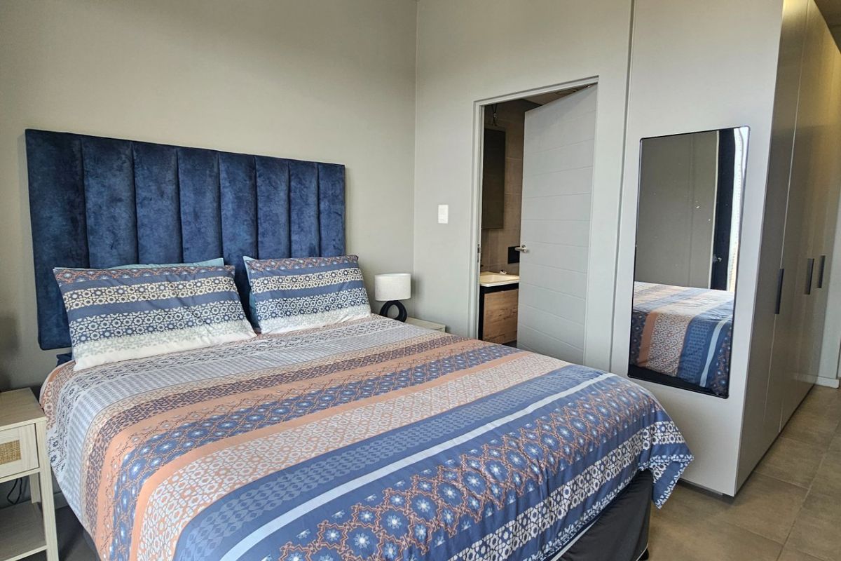 A well-maintained bedroom featuring built-in cupboards, tiled flooring, and direct access to an en-suite bathroom.