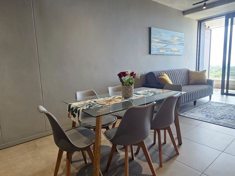 A modern open-plan living and dining area featuring large sliding glass doors that provide natural light and access to the balcony.