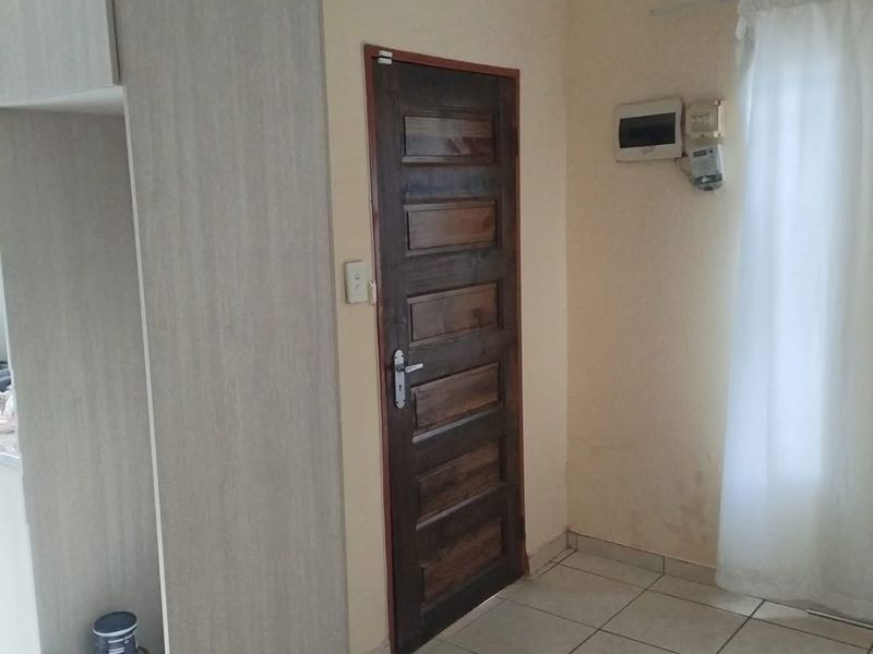 An entry area featuring tiled flooring, a wooden door, and built-in cabinetry, showing signs of wear and wall staining.