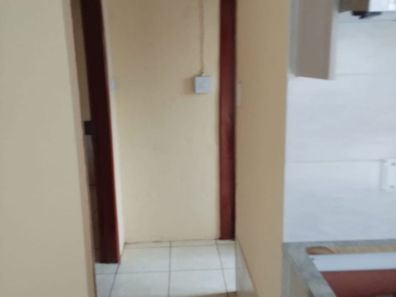 A view of a kitchen area featuring tiled flooring, built-in cabinetry, and an extractor fan, showing signs of unfinished work and exposed wiring.