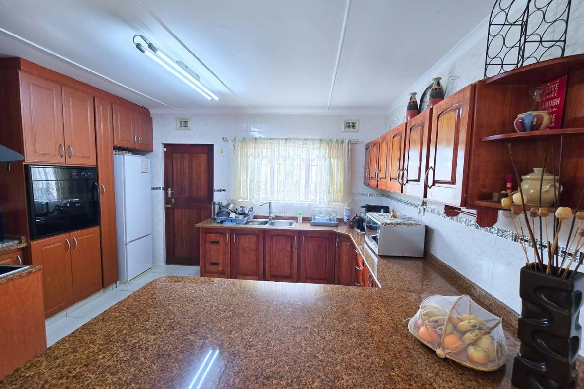 A functional kitchen featuring warm-toned wooden cabinetry, granite countertops, and a double bowl sink, offering a classic layout with ample storage space.