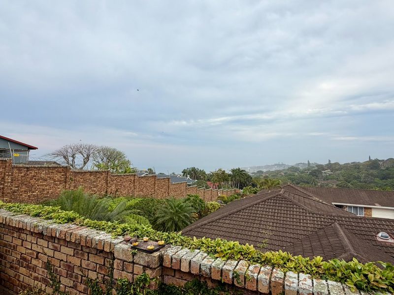 Elevated view overlooking the surrounding neighbourhood, featuring established brick boundary walls and neighbouring tiled roof structures with solar panel installations.