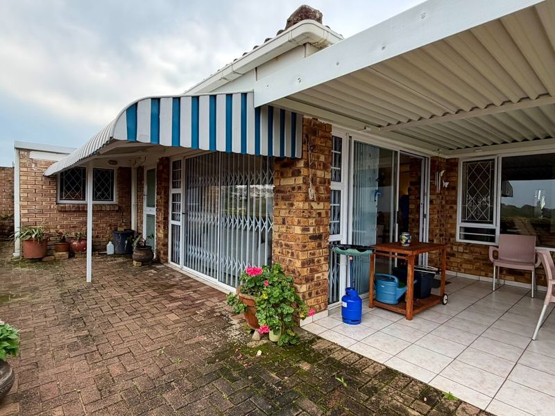 A covered patio area featuring brick walls, tiled flooring, and a striped awning, providing a functional outdoor space for relaxation and entertainment.